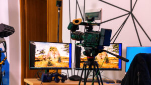 Professional video camera on a stand with monitors on a table