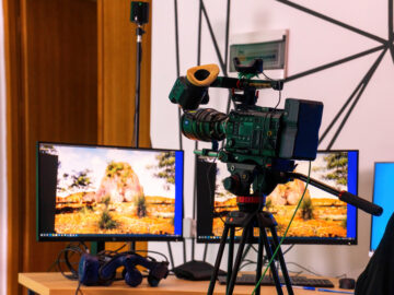 Professional video camera on a stand with monitors on a table